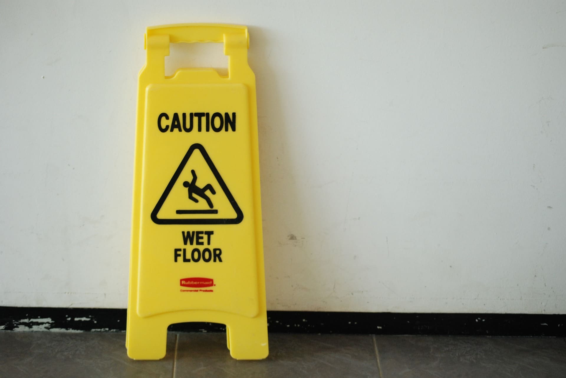Safety sign with phrase CAUTION WET FLOOR and mop bucket on