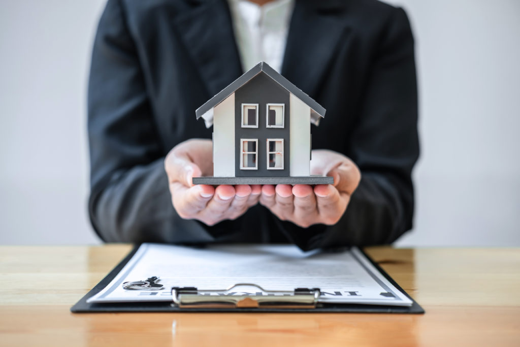 woman holding house model over document contract